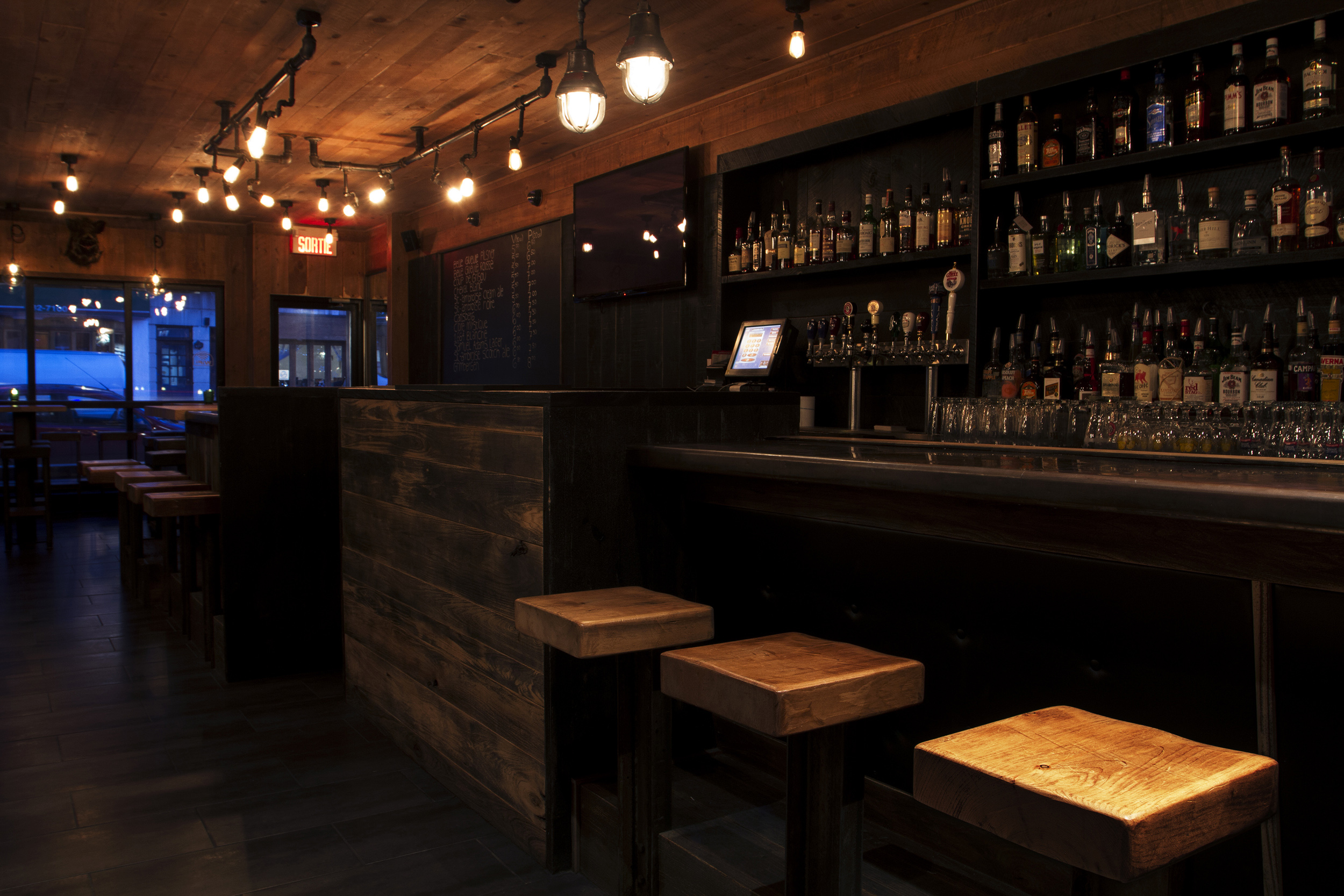Le comptoir en bois du bar le über, éclairé en soirée